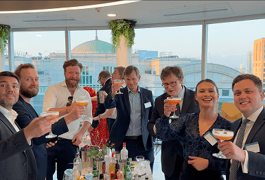 A group of corporate professionals raising cocktail glasses in a toast at a premium networking event