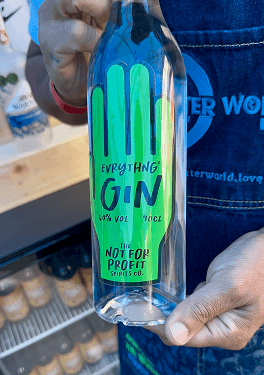 A close up of a bartender holding a bottle of Everything Gin from the not for profit spirits company