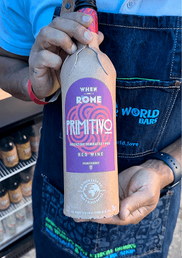 A bartender holding a paper bottle of When in Rome red wine at an ethical event bar