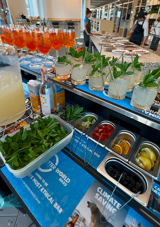 Aperol spritzes and mojitos lined up beside fresh garnish trays on the climate saving event bar