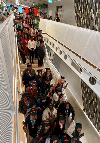 Outrunners Academy graduates in their mortarboards gathered along the Nike head office stairway