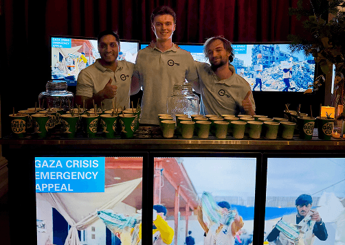 A bartender serving a guest wearing a tuxedo at a digital mobile bar inside a large event hall