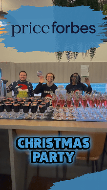 Three event bartenders wearing festive jumpers standing behind a pop-up mobile bar serving glasses of mulled wine at a Price Forbes corporate Christmas party.
