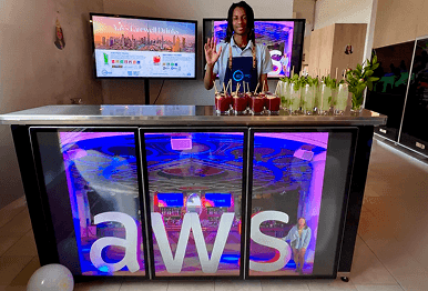 A professional bartender waving behind a high tech digital screen bar displaying custom AWS branding for a corporate farewell party