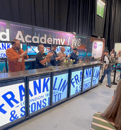 A large customisable digital screen bar serving as the focal point for an immersive brand experience on stage at a crowded industry trade show