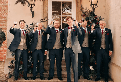 A groom and his groomsmen standing outside a beautiful building raising their glasses of red wine in a toast representing the joyous celebration detailed in your personalized wedding impact report